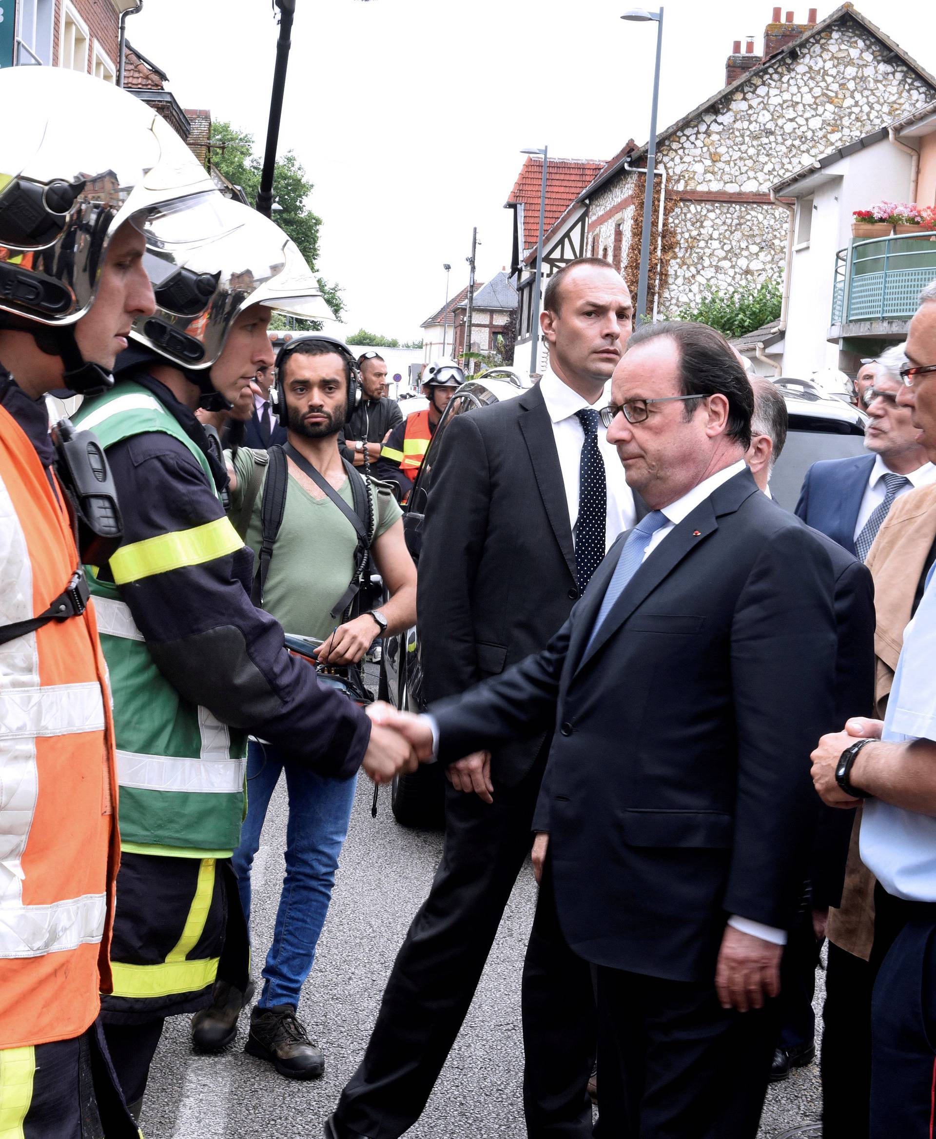 French President Francois Hollande shakes hands with French firemen as he arrives after a hostage-taking at a church in Saint-Etienne-du-Rouvray