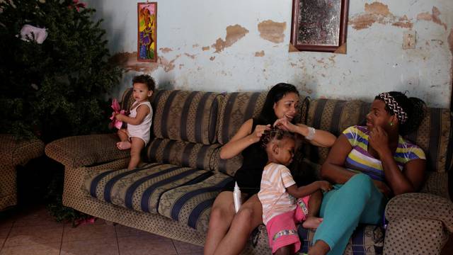 Women talk next to a Christmas tree in their home at the slum of Petare in Caracas