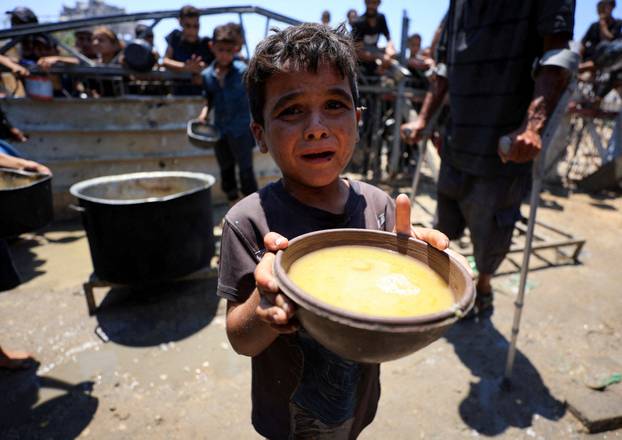 Palestinians wait to receive food from a charity kitchen, in Gaza City