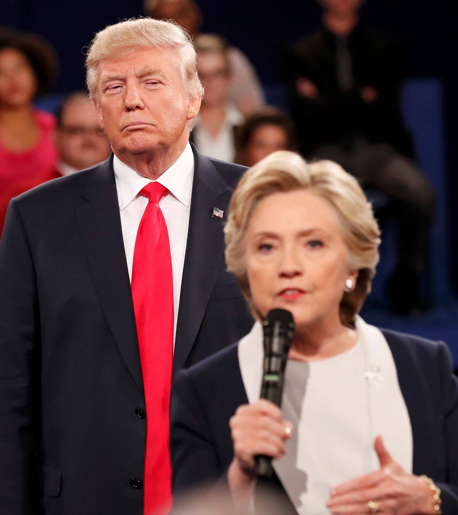 Republican U.S. presidential nominee Trump listens as Democratic nominee Clinton answers a question from the audience during their presidential town hall debate in St. Louis