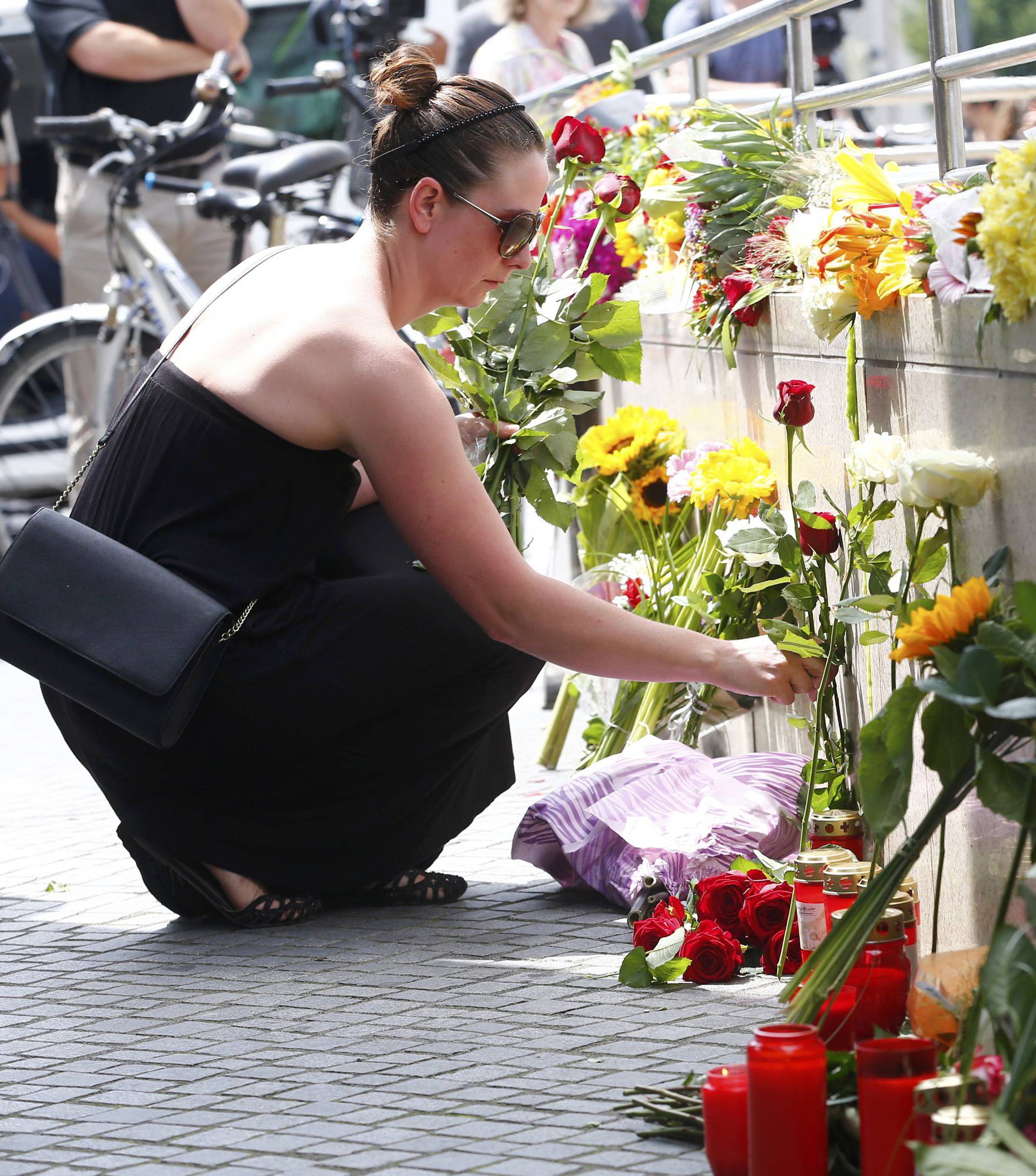 A women places flowers near Olympia shopping mall in Munich