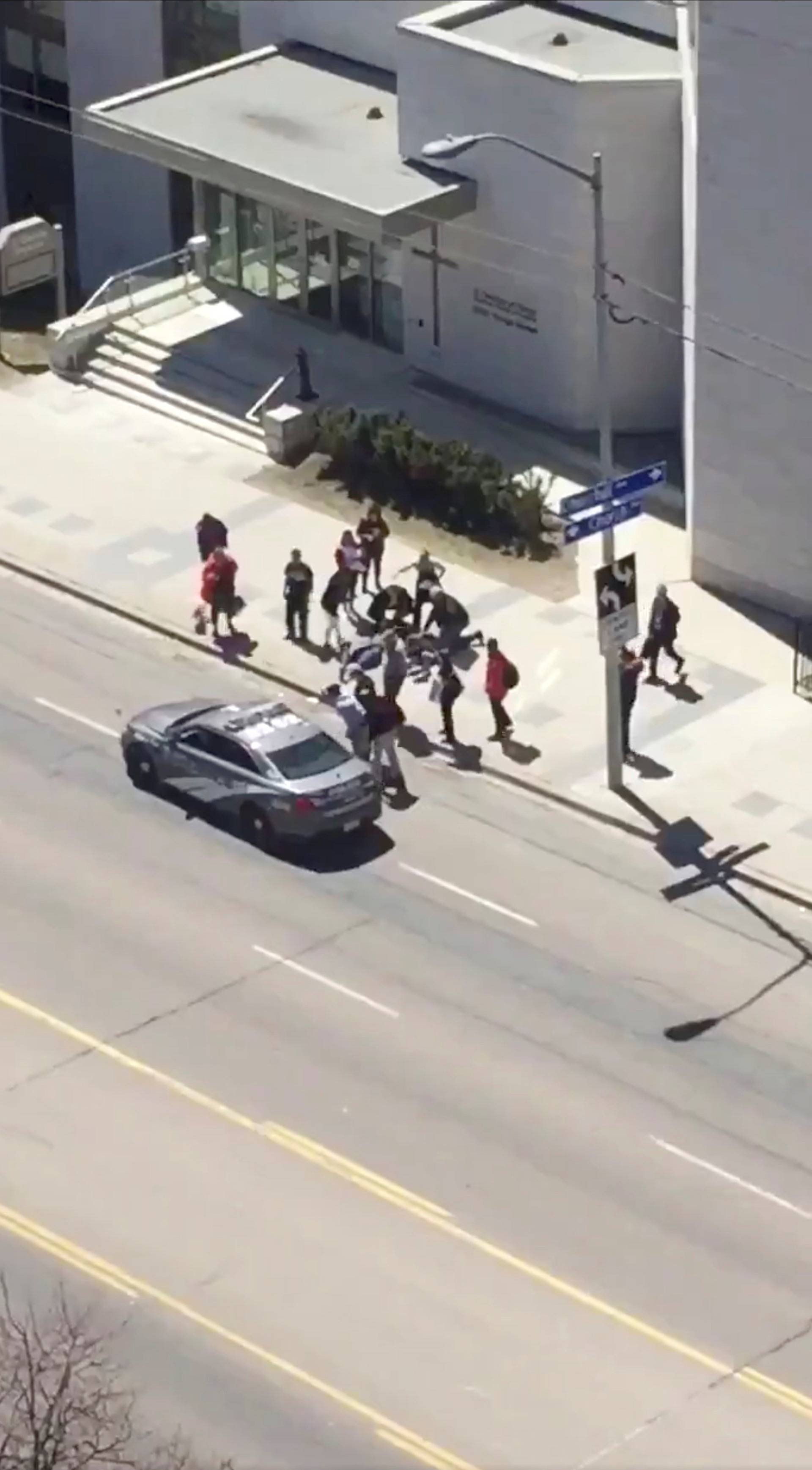 A victim is helped by pedestrians after a van hit multiple people at a major intersection in Toronto, Canada