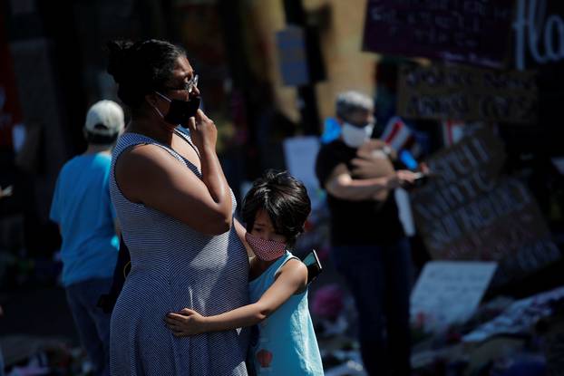 Sudha Setty and her daughter wearing protective face masks react at a makeshift memorial honoring George Floyd, at the spot where he was taken into custody, in Minneapolis