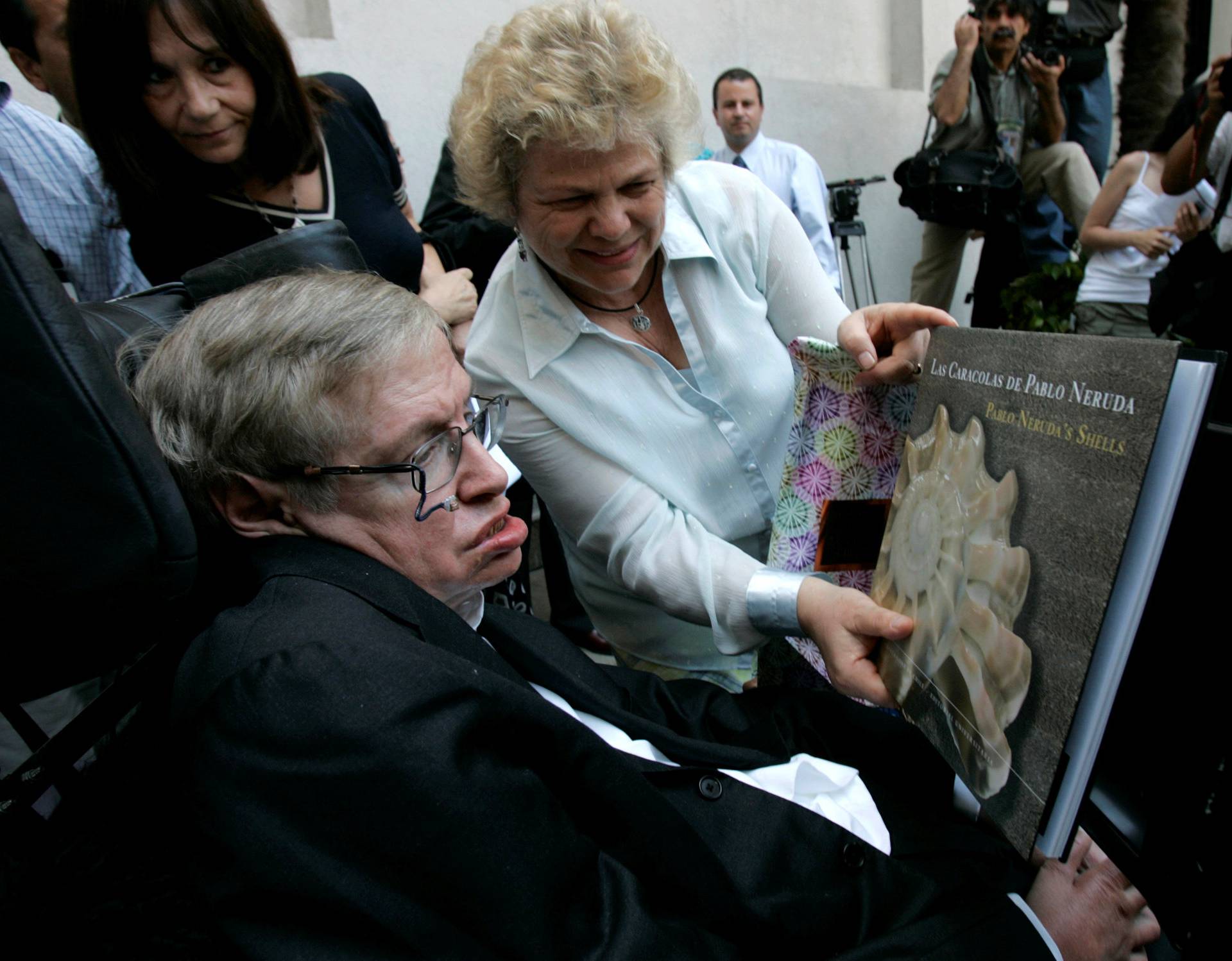 FILE PHOTO: British physicist Hawking looks at book of Chile's Nobel Laureate Neruda after meeting Chile's President Bachelet in Santiago