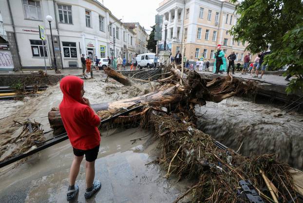 People gather in a street affected by flooding after heavy rainfall in Yalta