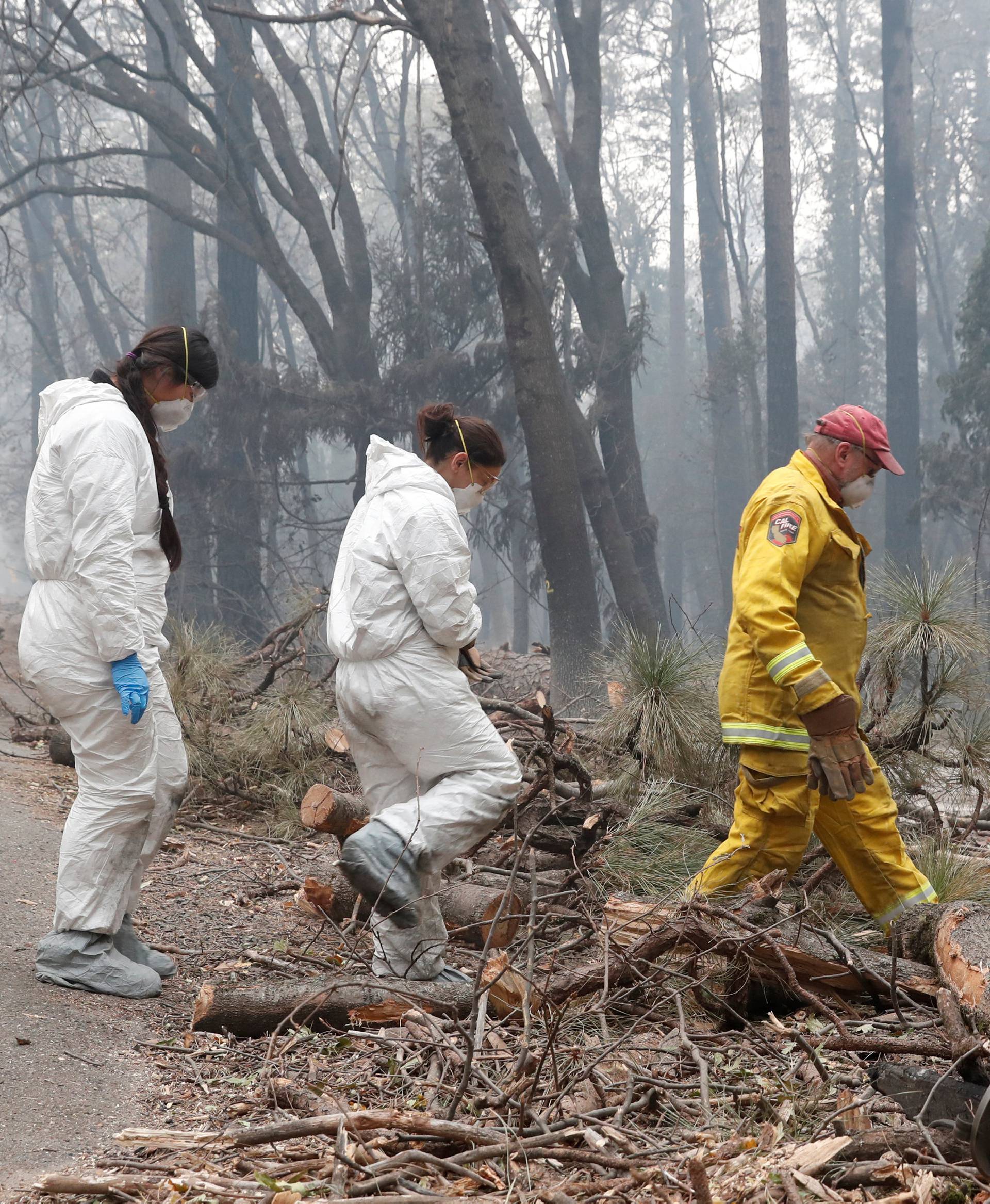 Firefighters and members of a volunteer search and rescue crew approach a house destroyed by the Camp Fire in Paradise