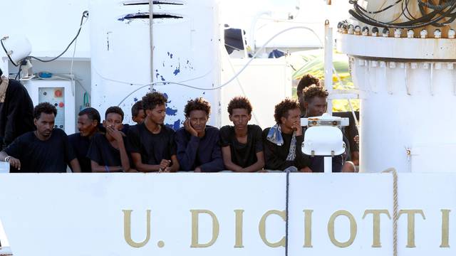 Migrants wait to disembark from the Italian coast guard vessel "Diciotti" at the port of Catania