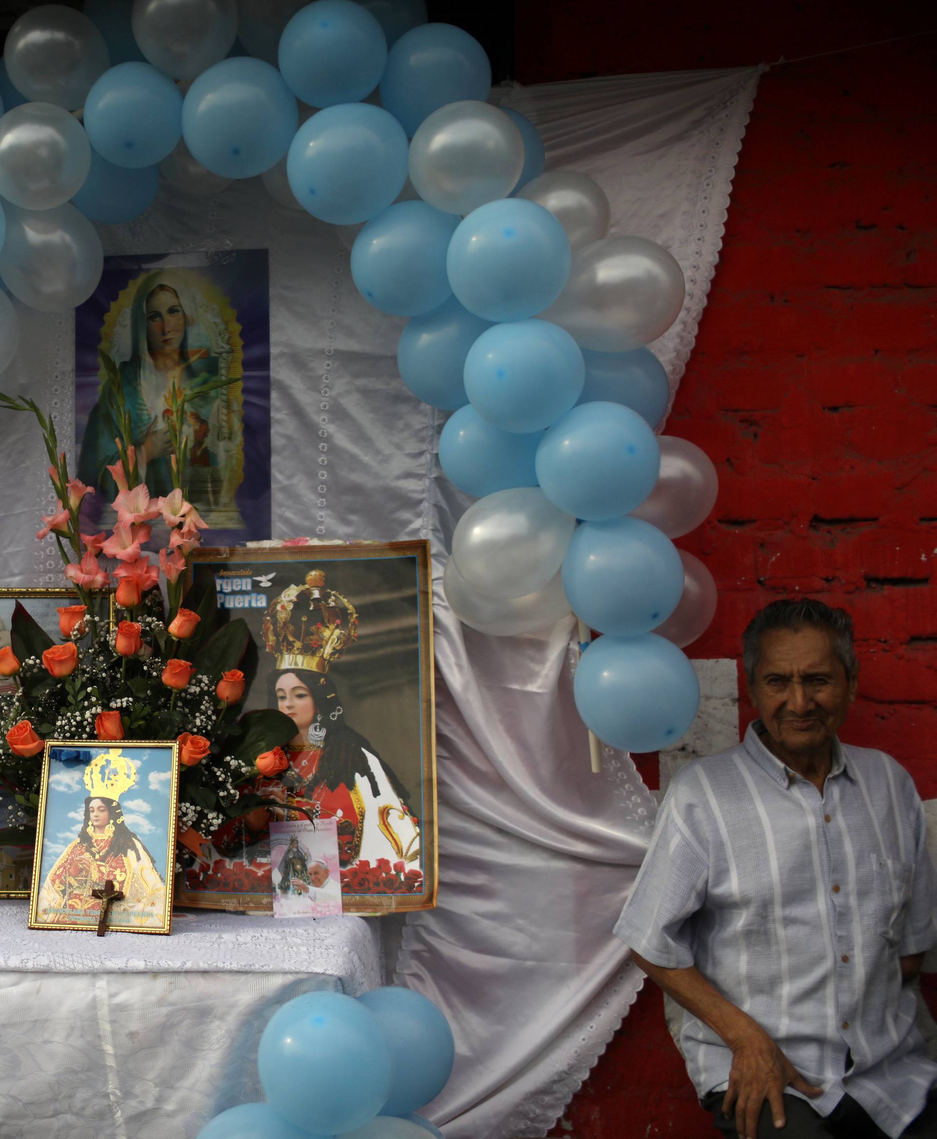 A family gather next to religious icons outside their house, prior to Pope Francis' visit, in Trujillo, Peru