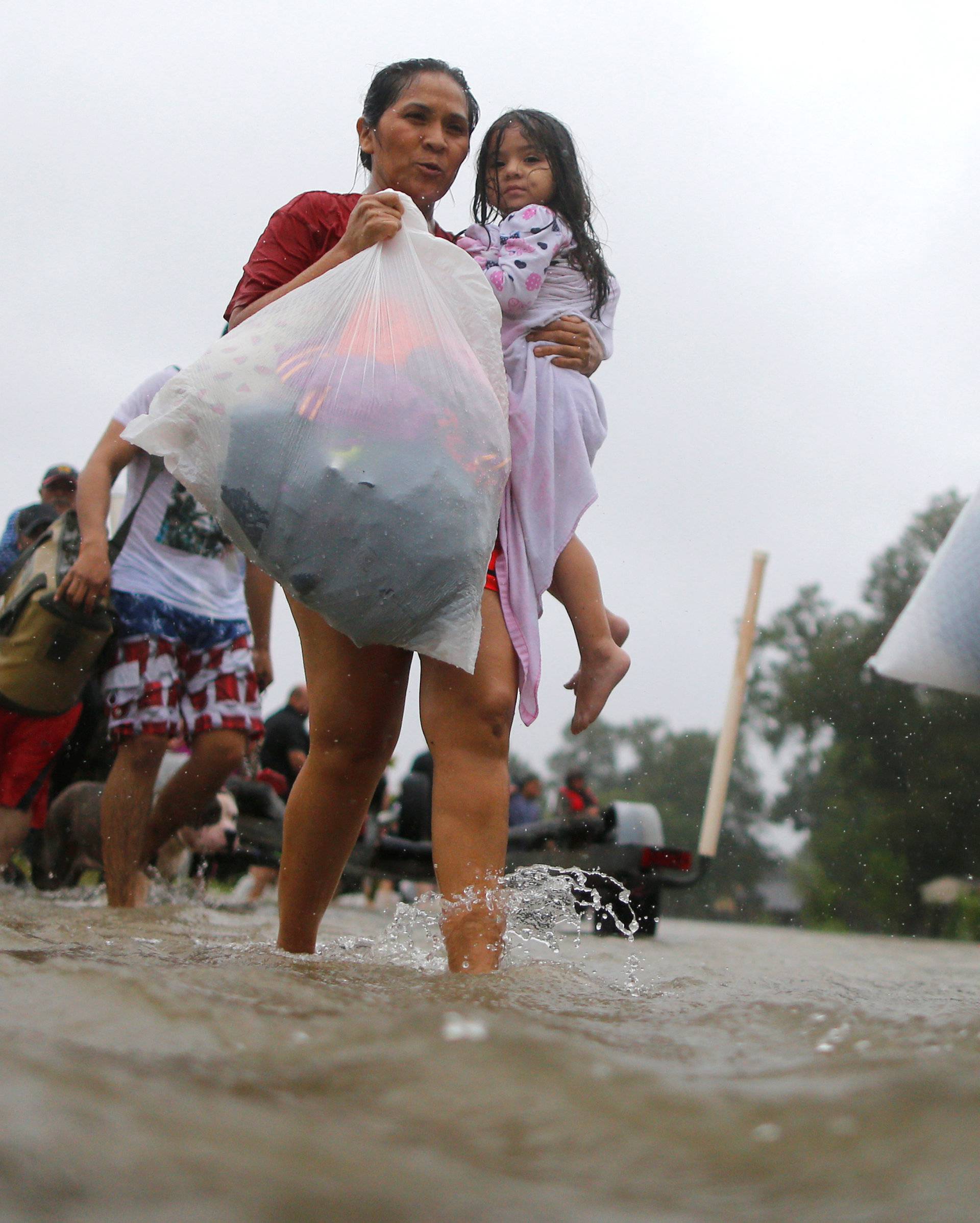 A woman and her daughter wade through flood waters from Tropical Storm Harvey after being rescued in east Houston