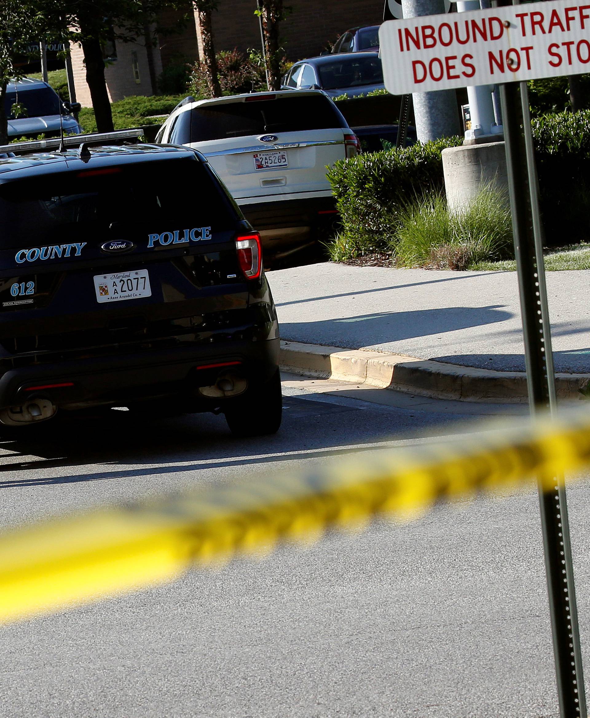 Police walk past a vehicle near a shooting scene at the Capital Gazette newspaper in Annapolis