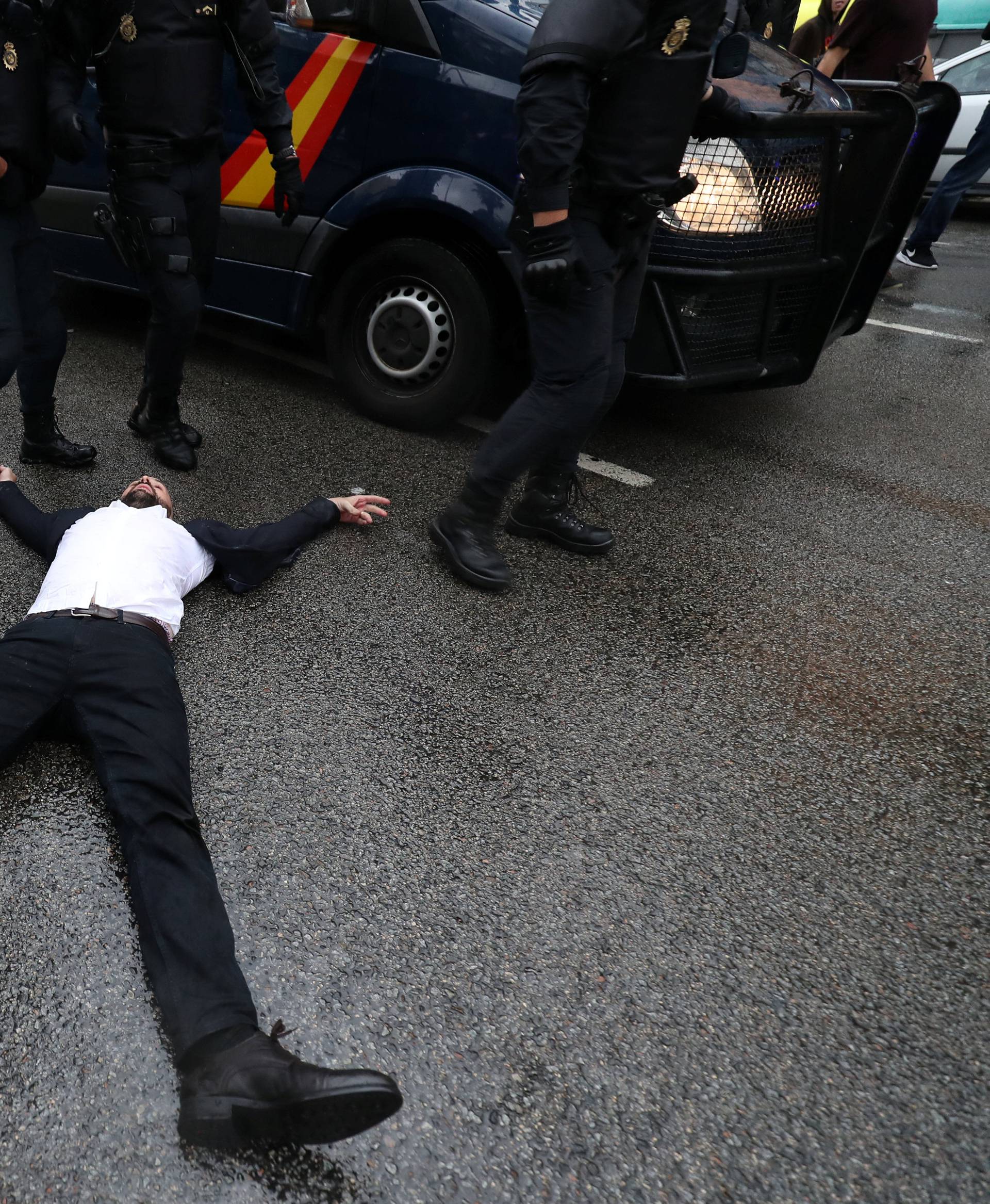 Riot police remove demonstrators outside a polling station for the banned independence referendum in Barcelona