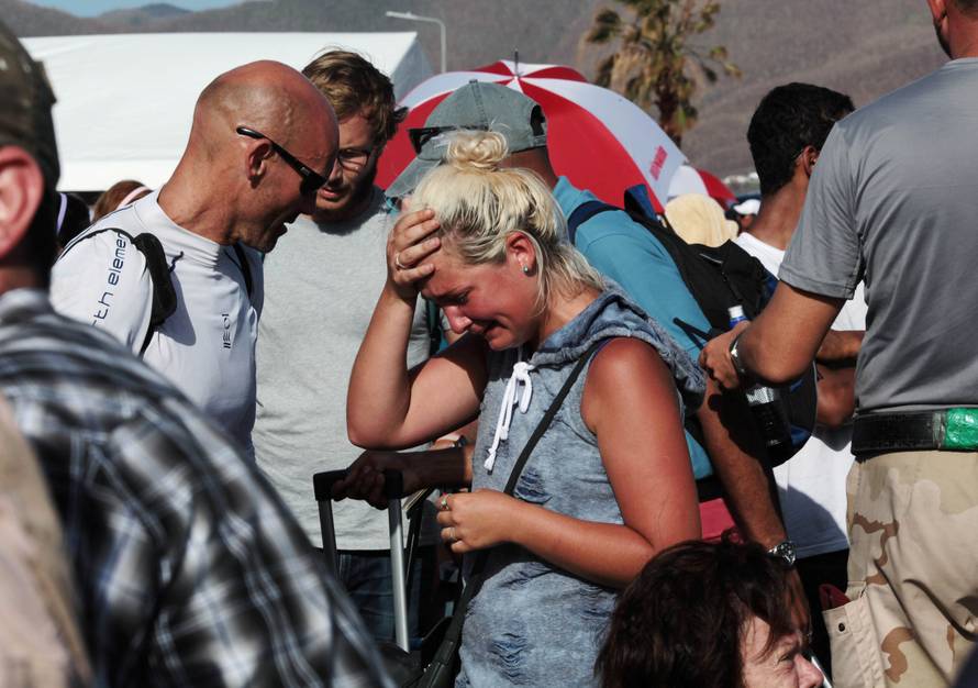 A woman reacts as she stands with others in line to board a plane and leave the island after it was devastated by Hurricane Irma, in Simpson Bay