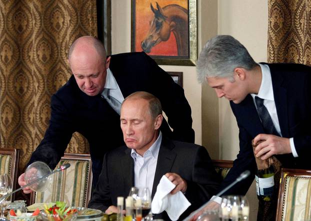 FILE PHOTO: Evgeny Prigozhin assists Russian Prime Minister Vladimir Putin during a dinner with foreign scholars and journalists at the restaurant Cheval Blanc on the premises of an equestrian complex outside Moscow