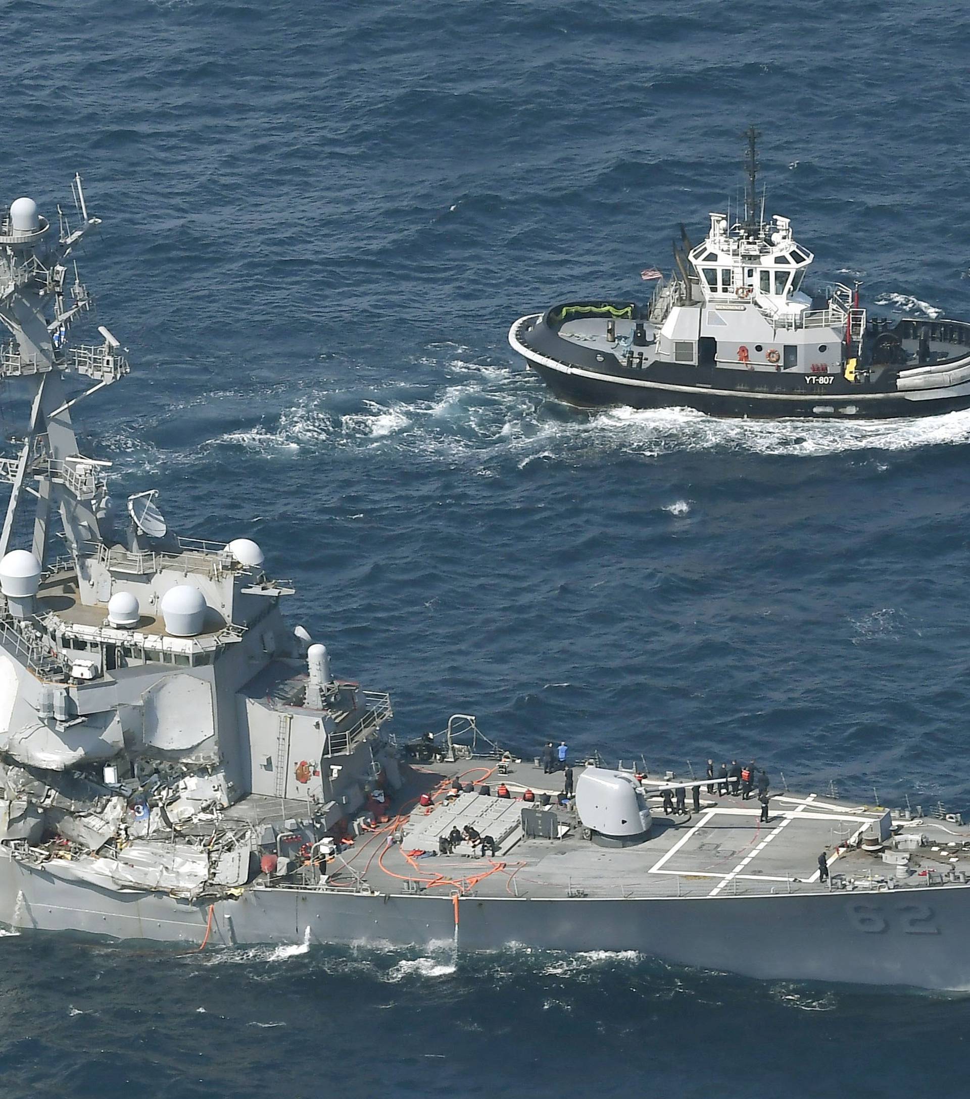 The Arleigh Burke-class guided-missile destroyer USS Fitzgerald, damaged by colliding with a Philippine-flagged merchant vessel, is seen next to a tugboat off Shimoda, Japan