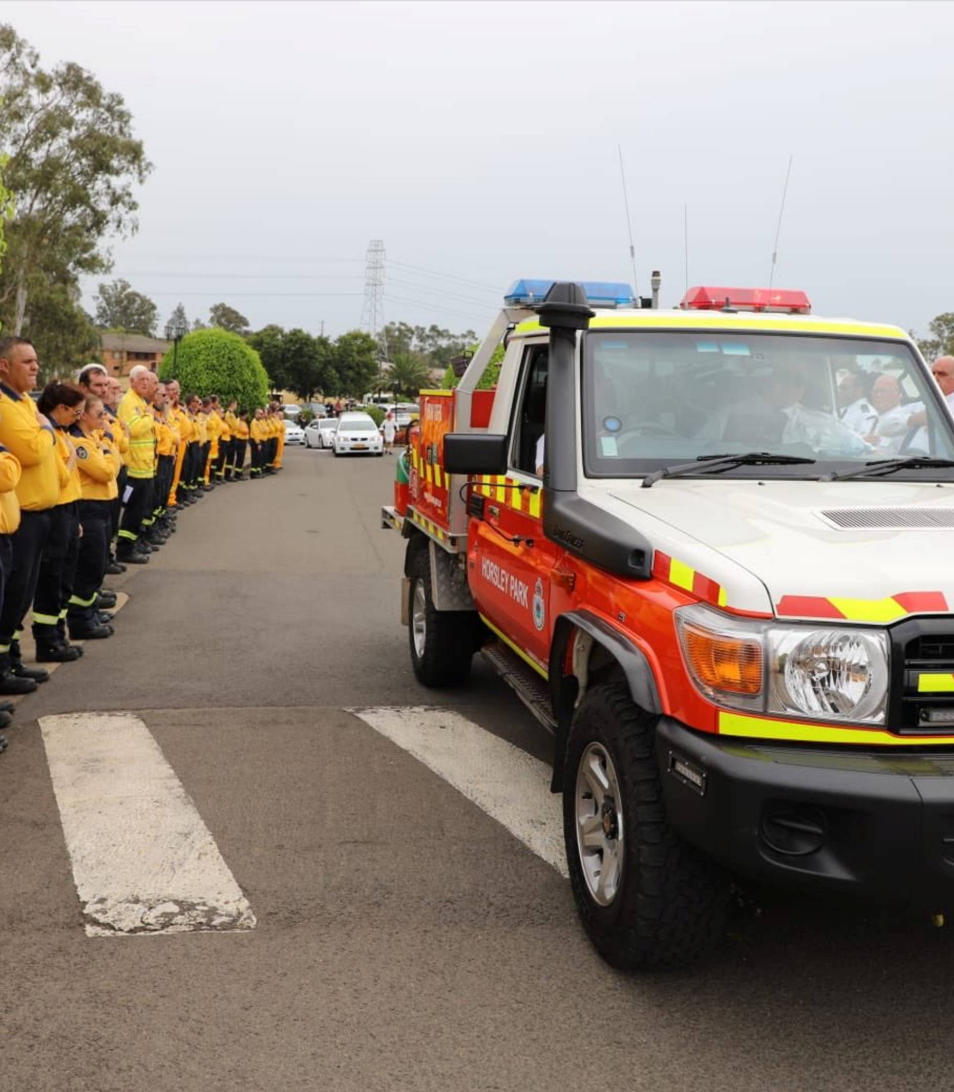 A car carrying the casket drives by as firefighters attend the funeral service of NSF RFS volunteer Andrew O'Dwyer in Sydney