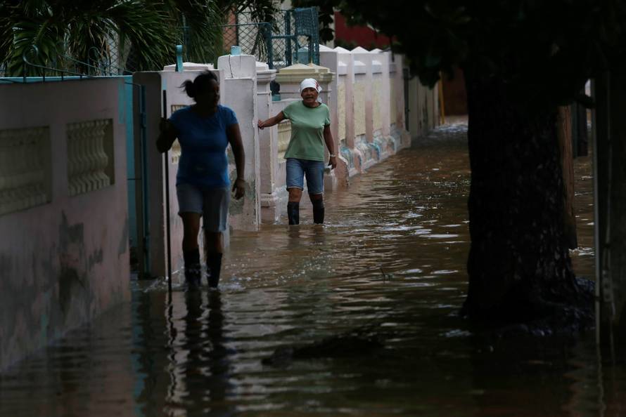 Women wade through a flooded street as Hurricane Irma turns toward the Florida Keys on Saturday, in Havana