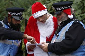 A man dressed as Santa Claus talks to a Police officer during the Santacon event in London