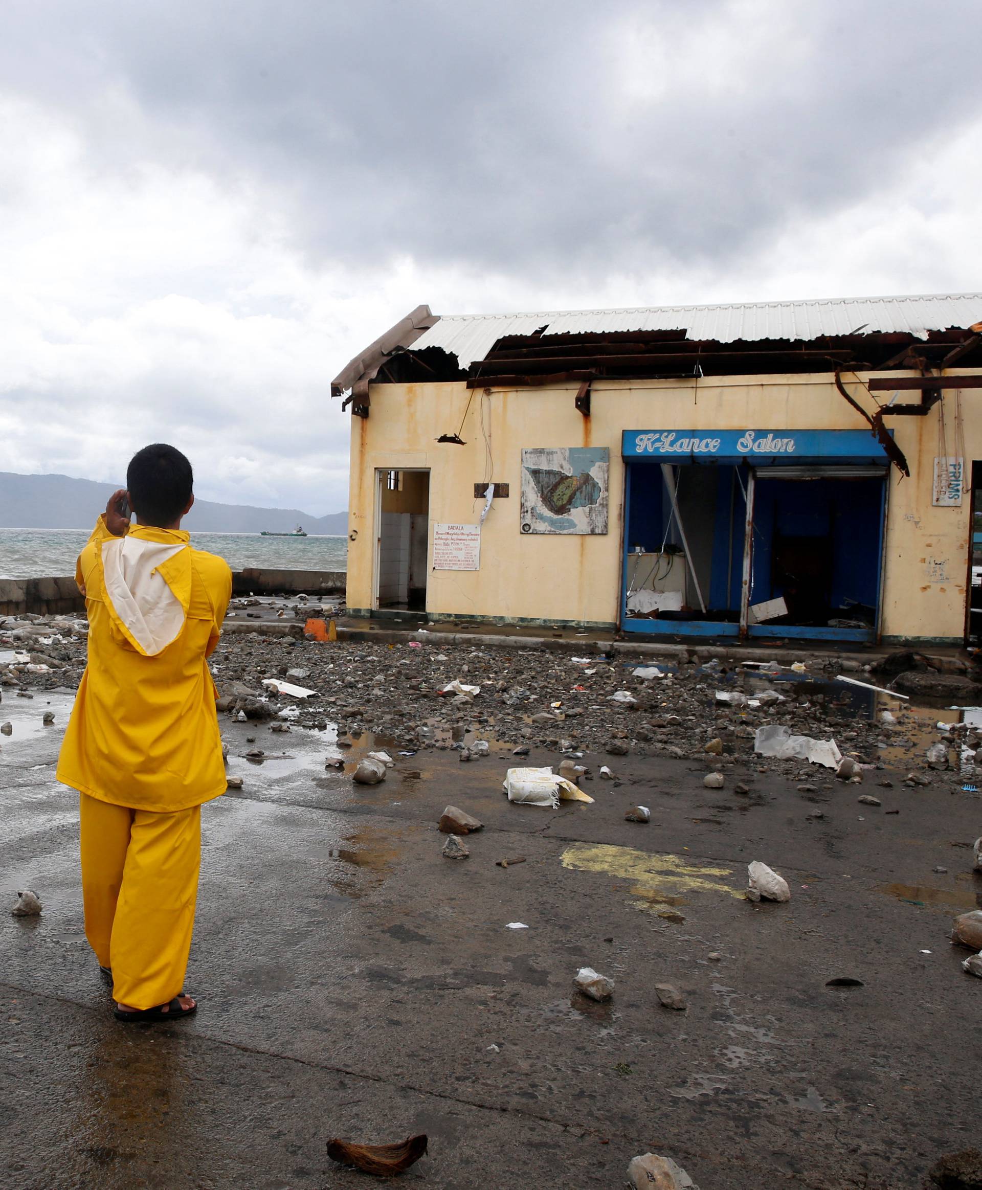 A port worker stands amidst debris swept from the sea at the height of Typhoon Nock-Ten in Mabini, Batangas, in the Philippines