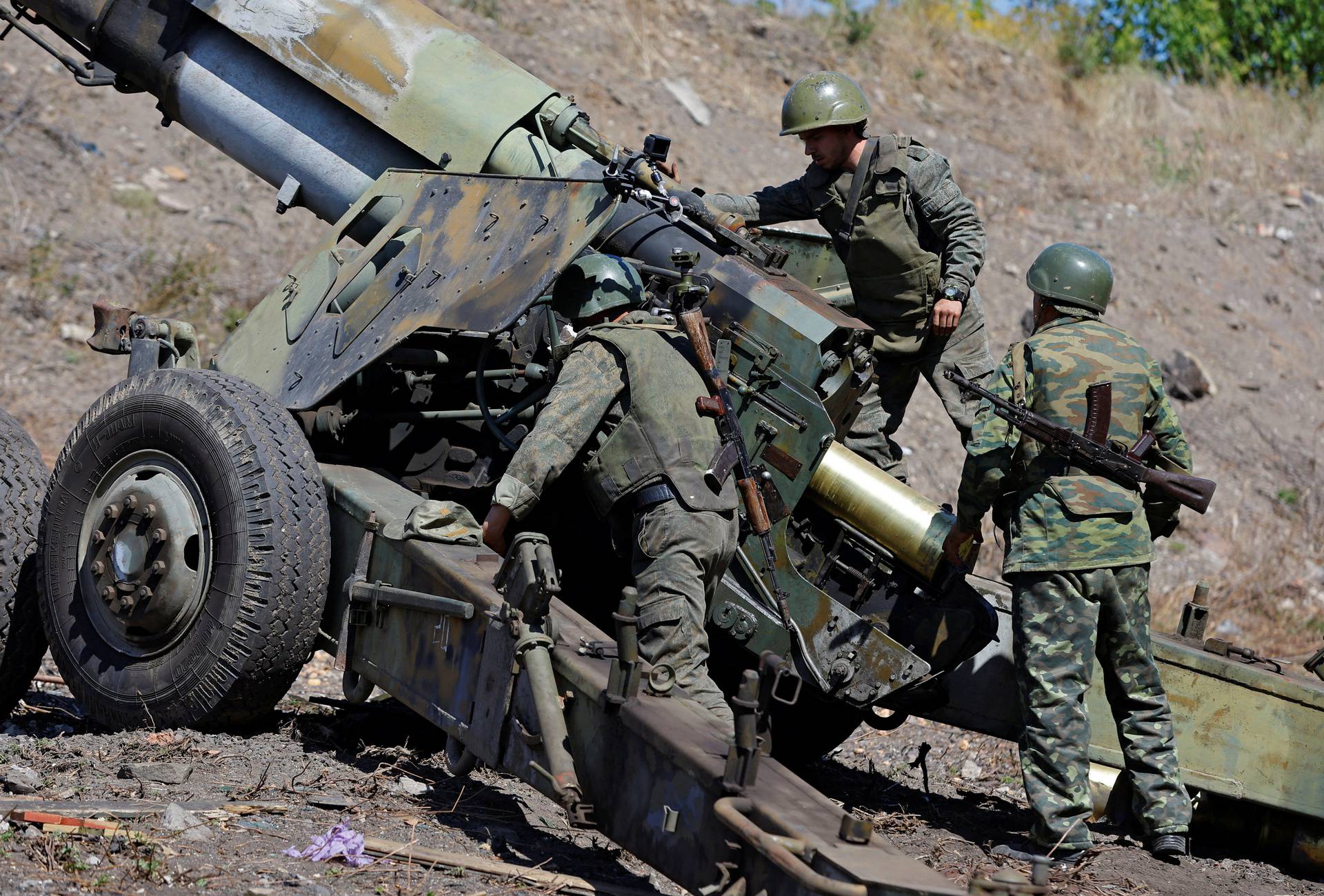 Service members of the self-proclaimed Donetsk People's Republic fire a Giatsint-B howitzer outside Donetsk