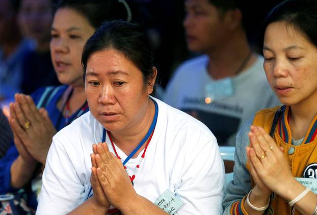 Family members pray near the Tham Luang cave complex, as an ongoing search for members of an under-16 soccer team and their coach continues, in the northern province of Chiang Rai