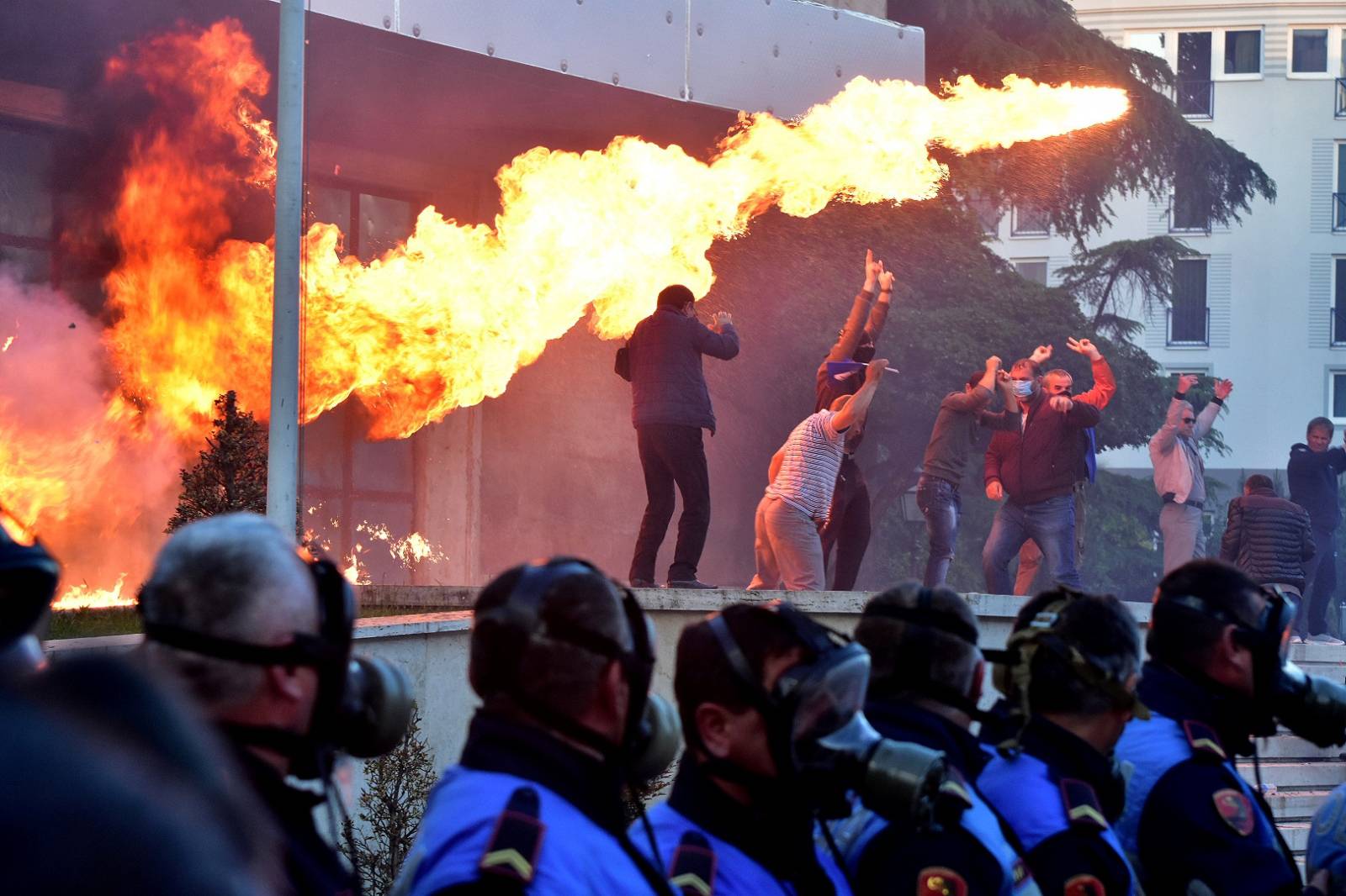 Flames are pictured behind a police formation during an anti-government protest in front of Prime Minister Edi Rama's office in Tirana