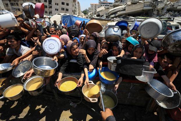 Palestinians wait to receive food from a charity kitchen, in Gaza City