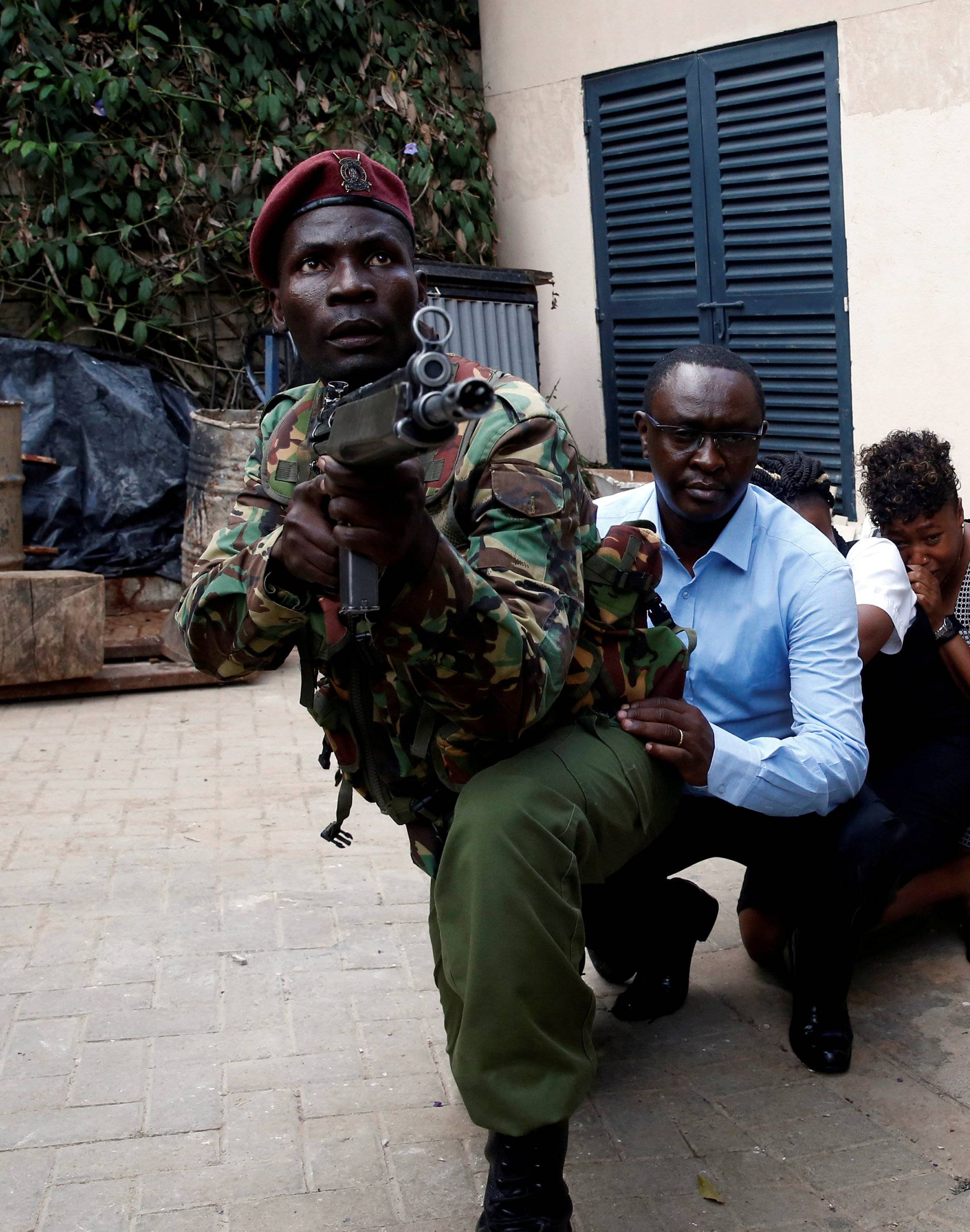 People are evacuated by a member of security forces at the scene where explosions and gunshots were heard at the Dusit hotel compound, in Nairobi