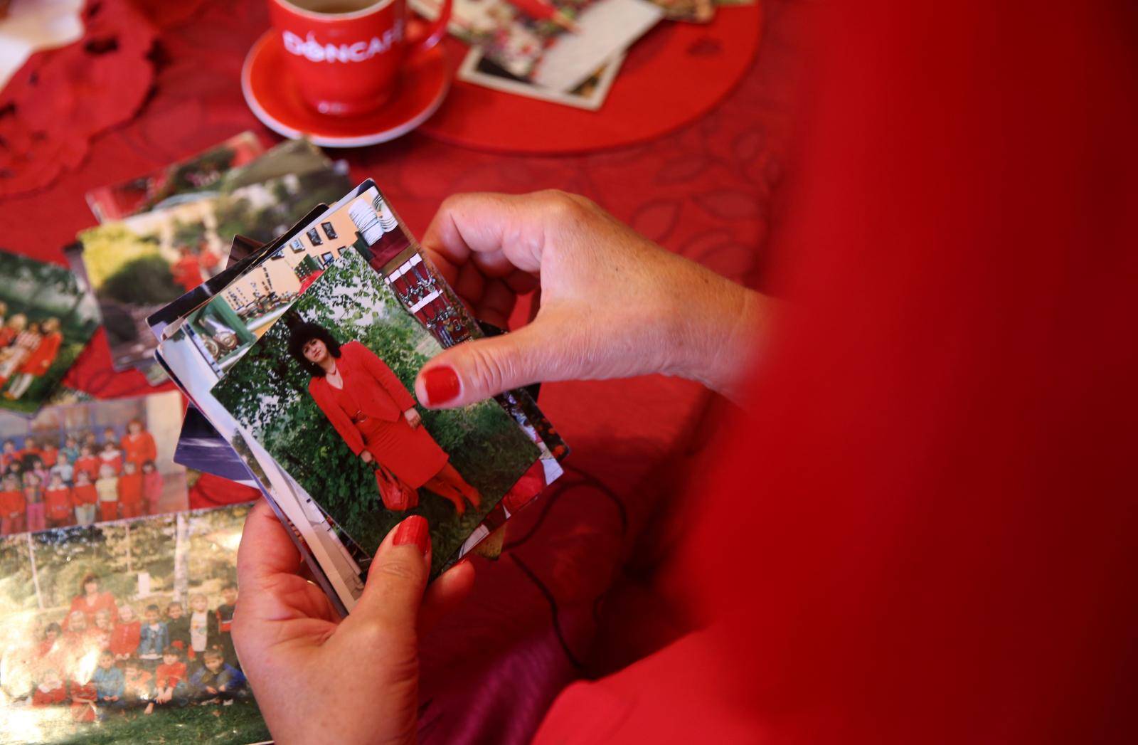 Zorica Rebernik, obsessed with the red color, looks at pictures from the period when she was a teacher, in her house in the village of Breze near Tuzla