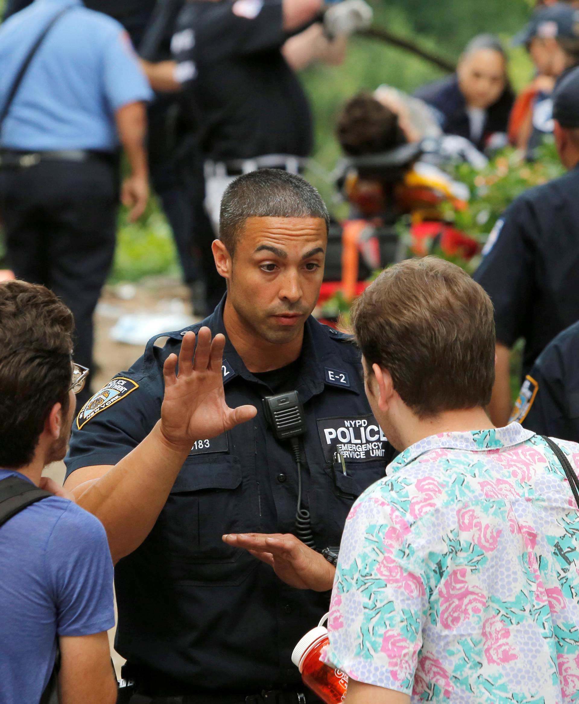 Police speak to people at the scene where a man was injured after an explosion in Central Park in Manhattan, New York