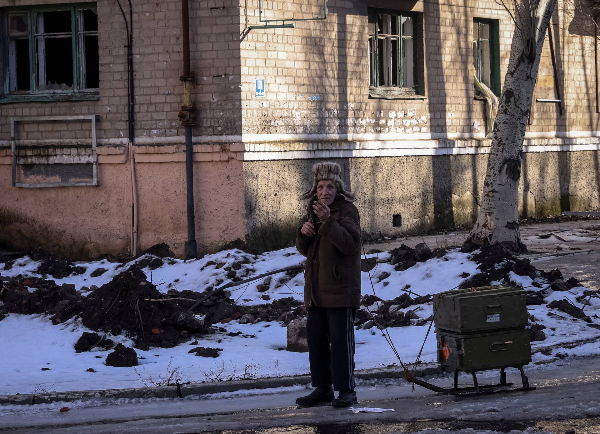 A local resident rests as he walks with empty ammunition boxes on street in Bakhmut