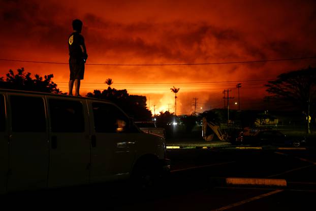 A man watches as lava lights up the sky above Pahoa