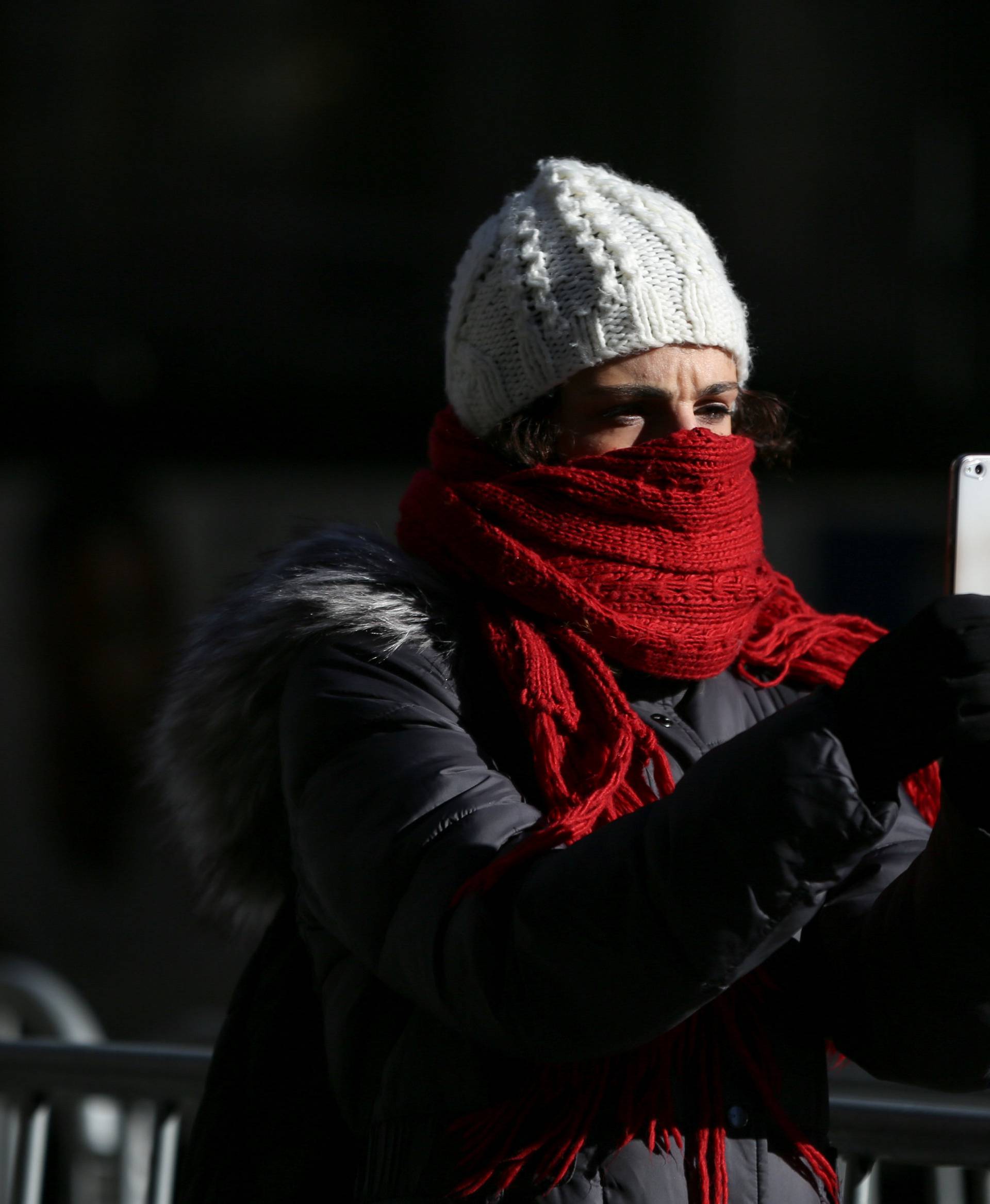 A woman takes a picture as she bundles up against the cold temperature in Times Square in New York