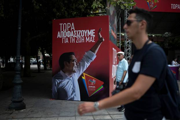 People walk past a poster depicting Greek PM Tsipras at the election kiosk of the leftist Syriza party in Athens