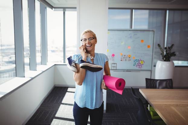 Smiling,Executive,Talking,On,Mobile,Phone,While,Holding,Exercise,Mat