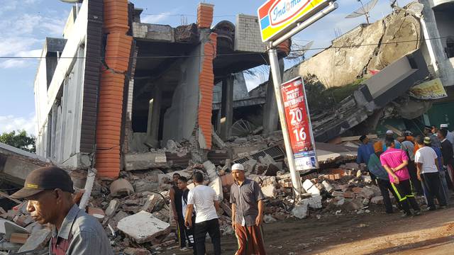 People survey the damage after dozens of buildings collapsed following a 6.4 magnitude earthquake in Ule Glee, Pidie Jaya in the northern province of Aceh, Indonesia