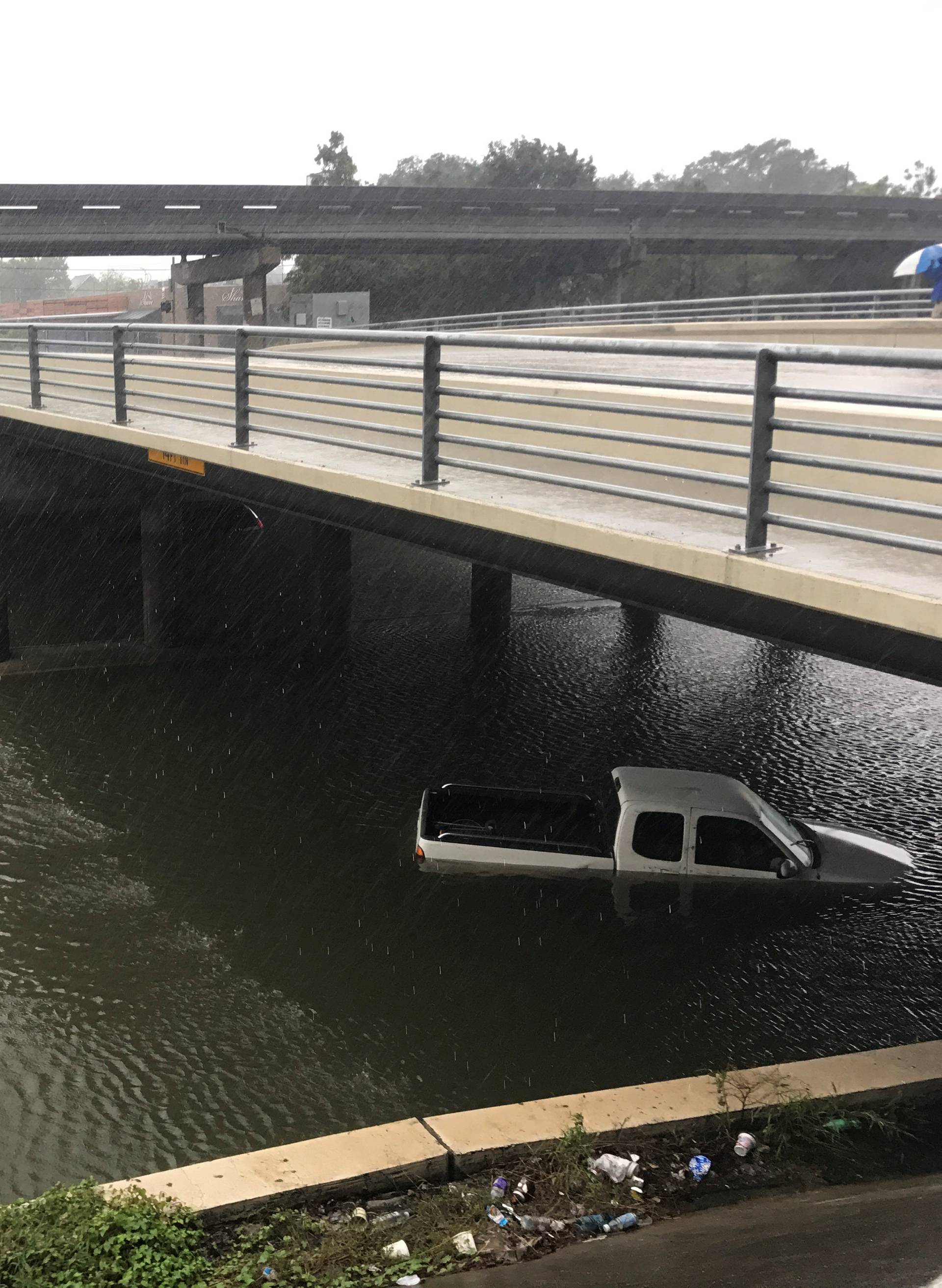 Vehicles sit half submerged in flood waters under a bridge in the aftermath of Hurricane Harvey in Houston