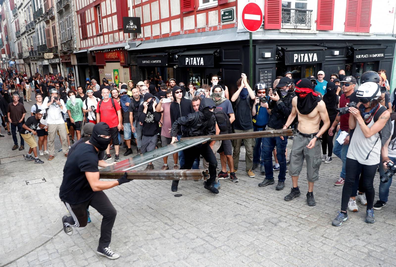 Demonstrators throw a part of a barricade at a police blockade during a protest against G7 summit, in Bayonne
