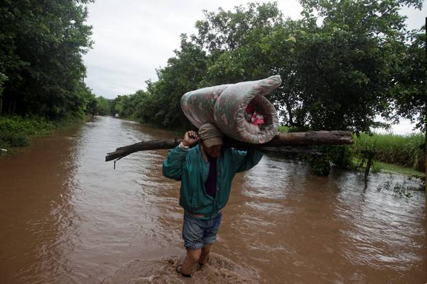 Man carries his belongings through a flooded road after the passing of Storm Iota, in Marcovia