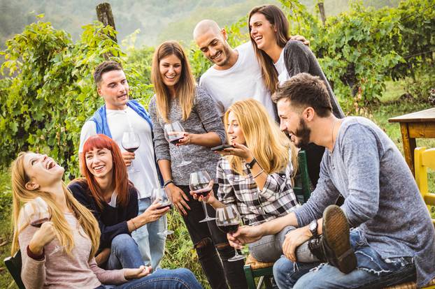 Happy friends having fun outdoor - Young people drinking red win