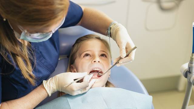 Dentists with a patient during a dental intervention to girl.