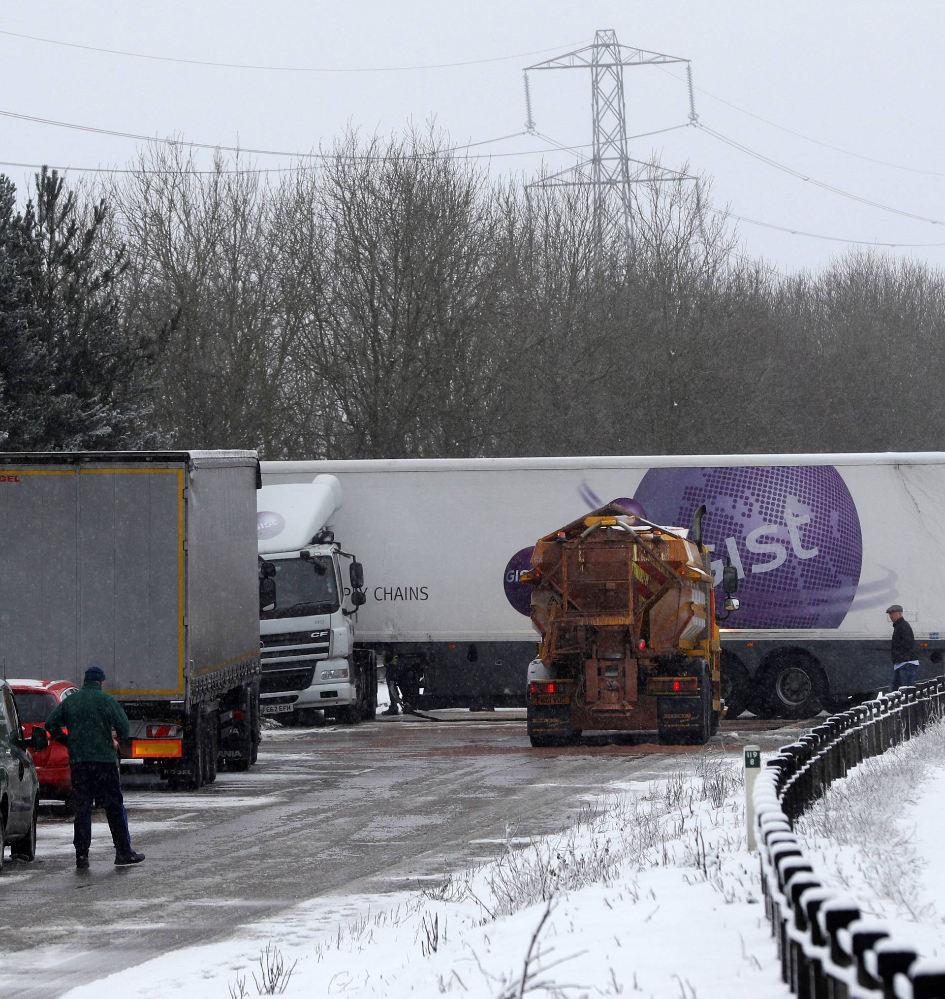 A crashed lorry on the A50 is tended to by police as the snow falls near Uttoxeter