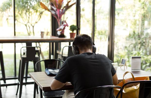 Asian student studying in  the cafe with headphones 
