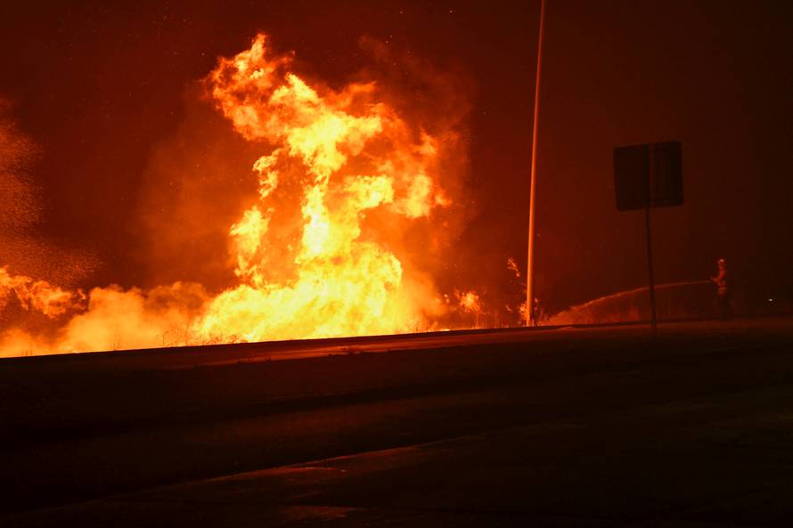 A firefighter battles a wind-driven wildfire in Sylmar, California