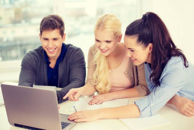 three smiling students with laptop and notebooks