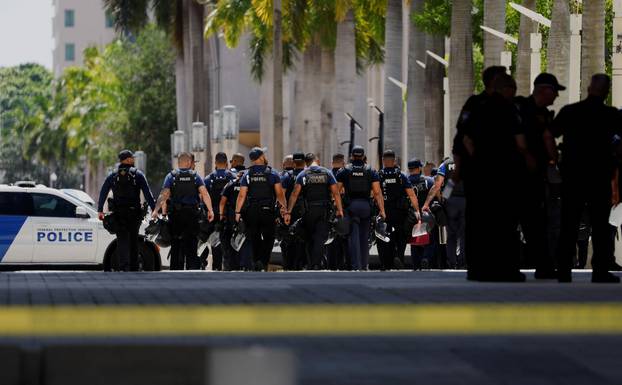 Police officers carrying helmets walk near the entrance of the Wilkie D. Ferguson Jr. United States Courthouse building, in Miami