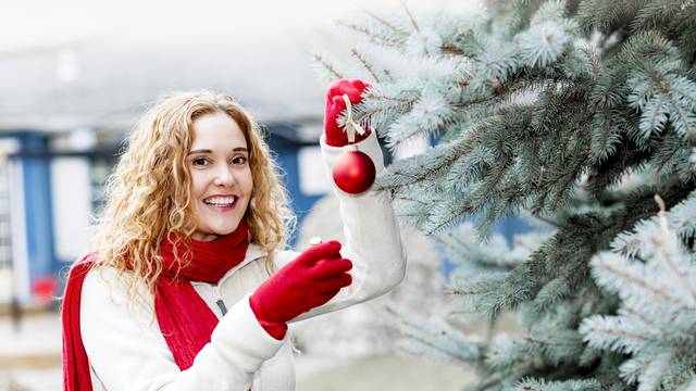 Woman decorating Christmas tree outside