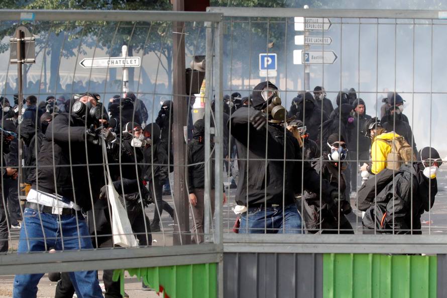 Tear gas floats around masked protesters during clashes with French CRS riot police at the May Day labour union rally in Paris