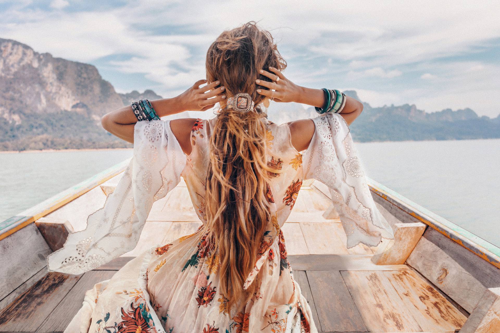 fashionable young model in boho style dress on boat at the lake