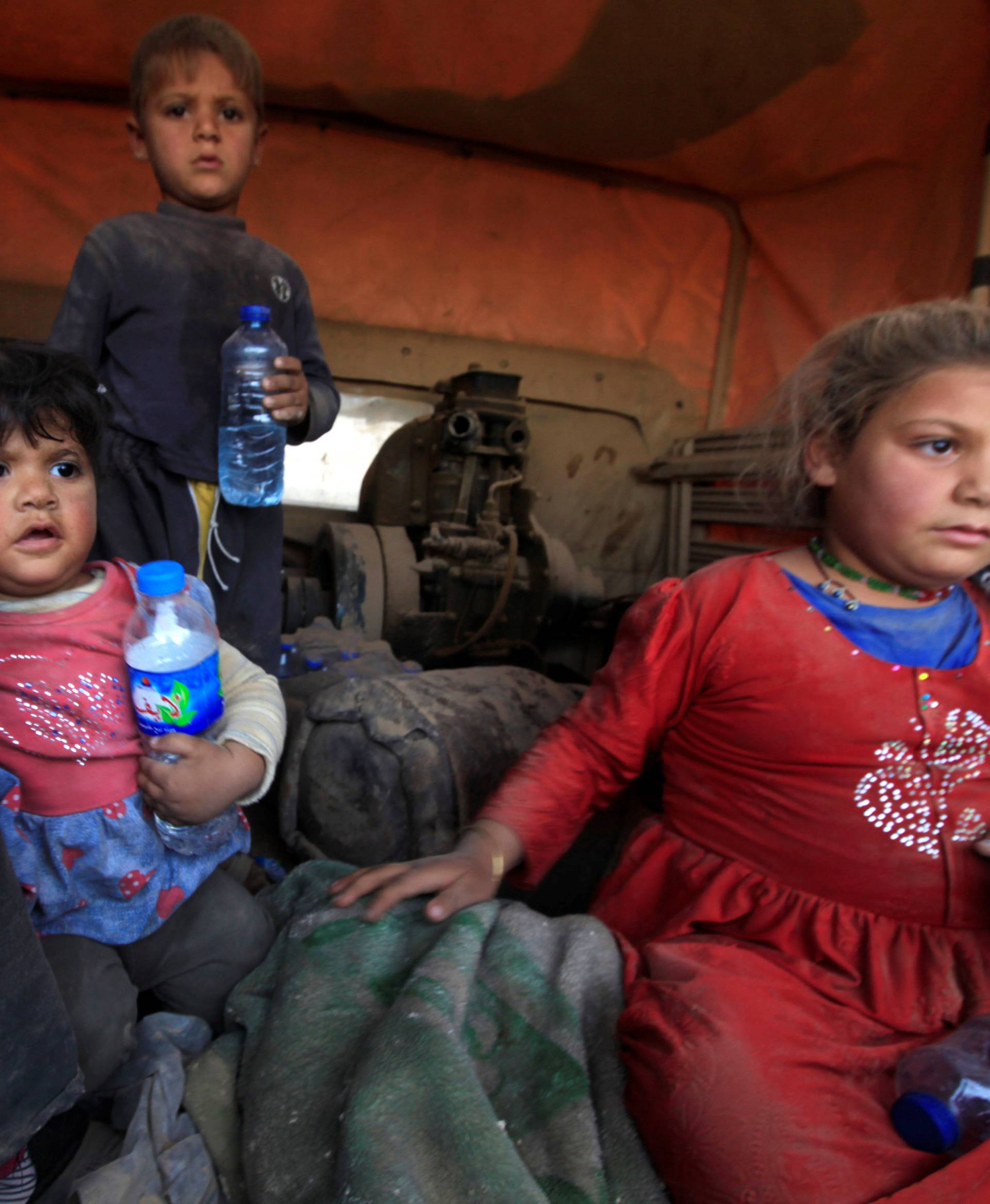 Displaced people who are fleeing from clashes sit in a military vehicle in Qayyarah, during an operation to attack Islamic State militants in Mosul