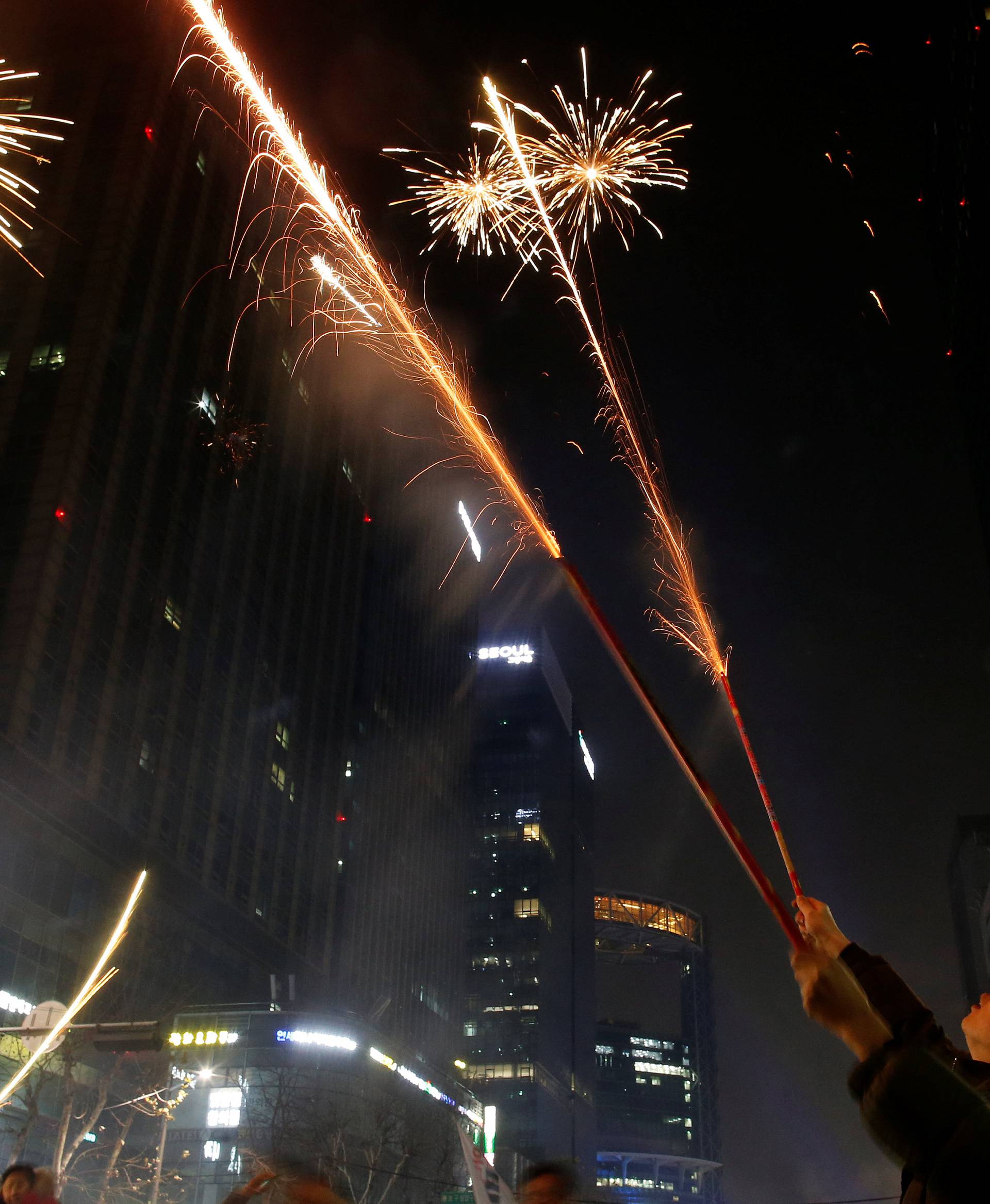 People set off fireworks as they attend a ceremony to celebrate the new year after a protest demanding South Korean President Park Geun-hye's resignation, in Seoul